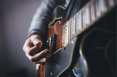Photo: A musician strumming the strings of an electric guitar.
